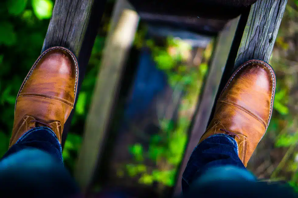 Photographie de pieds se tenant sur des morceaux de bois au dessus du vide